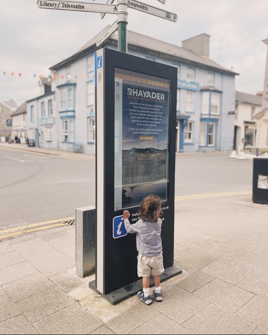 A child at the touch-screen town information point outside The Old Swan in Rhayader